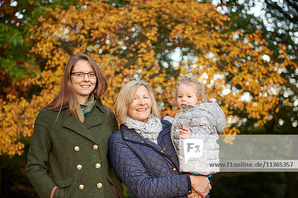 Portrait of senior woman with daughter and granddaughter in autumn park