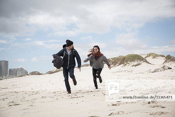 Young couple running on windswept beach  Western Cape  South Africa