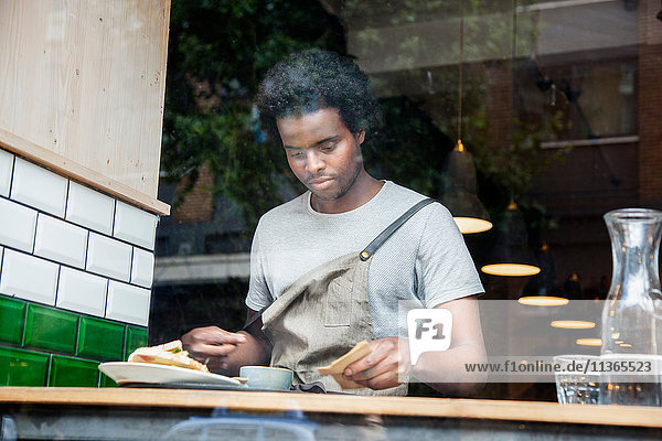 Kellner bei der Vorbereitung der Bestellung am Café-Fenster