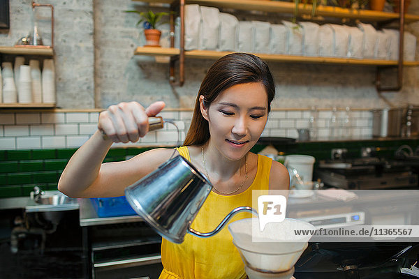 Female barista preparing filter coffee in cafe