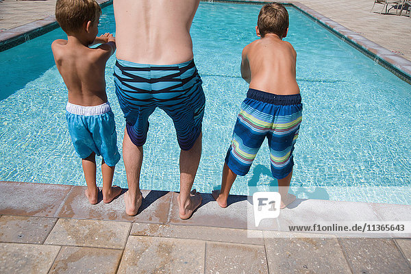 Rückansicht eines Mannes und zweier Söhne  die am Pool tauchen üben  Laguna Beach  Kalifornien  USA