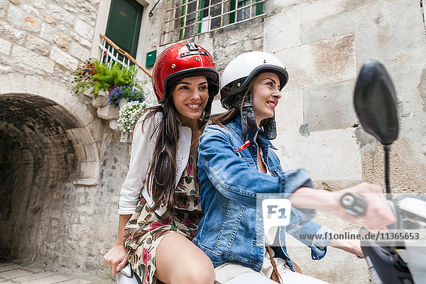 Female tourists riding moped through village  Split  Dalmatia  Croatia