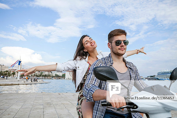 Young couple riding moped at harbour  Split  Dalmatia  Croatia