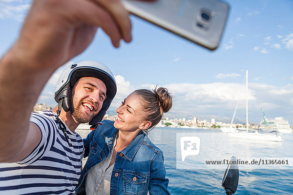 Young moped couple taking selfie on harbour  Split  Dalmatia  Croatia