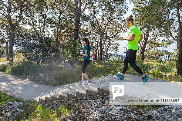Male and female runners running down park stairway  Split  Dalmatia  Croatia