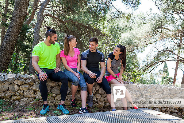 Four male and female runners chatting on park wall  Split  Dalmatia  Croatia