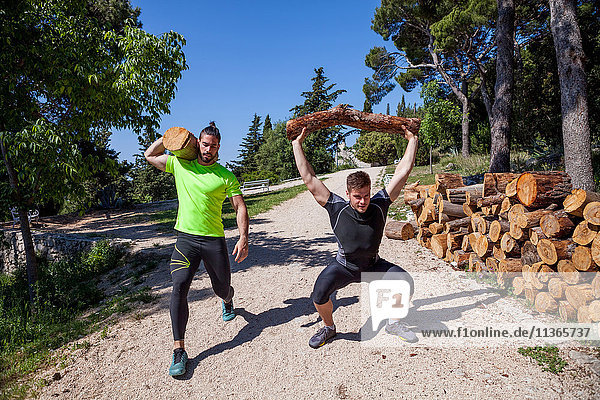 Zwei junge Männer machen Gewichthebertraining mit Baumstämmen im Wald  Split  Dalmatien  Kroatien