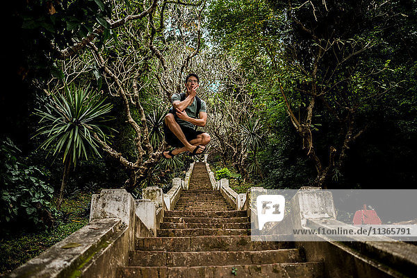 Man in mid air on steps to Mount Phousi  Luang Prabang  Laos