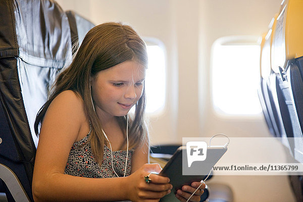 Junges Mädchen benutzt digitales Tablett im Flugzeug