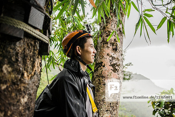 Young man by tree wearing climbing helmet looking away  Ban Nongluang  Champassak province  Paksong  Laos