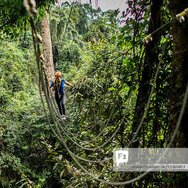 Frau überquert Seilbrücke im Wald  Ban Nongluang  Provinz Champassak  Paksong  Laos