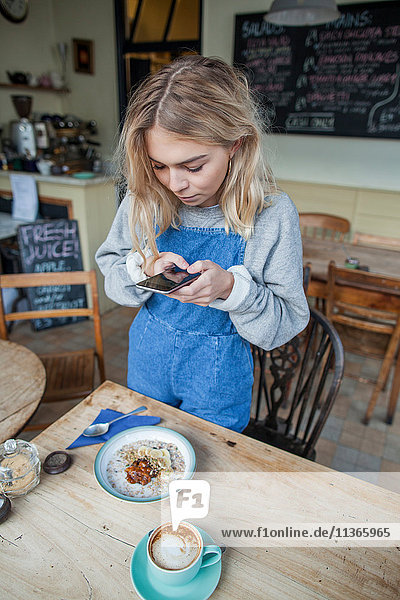 Junge Frau im Cafe,  mit Smartphone
