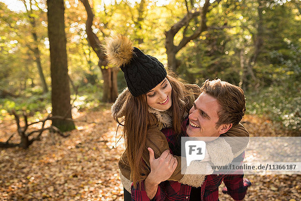 Young couple in forest  young man giving young woman piggyback  laughing