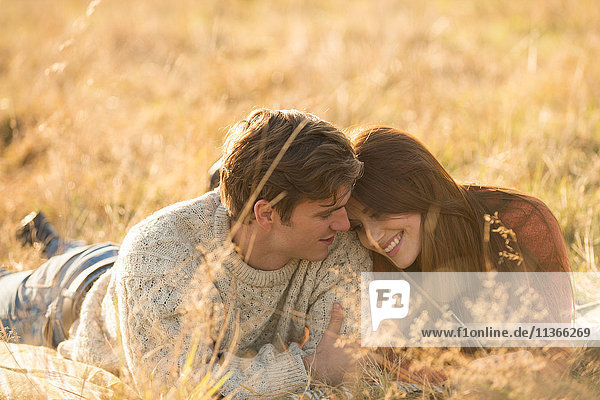 Junges Paar auf dem Feld liegend  lächelnd