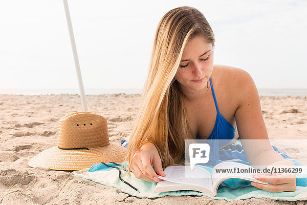 Junge Frau liest Buch am Strand