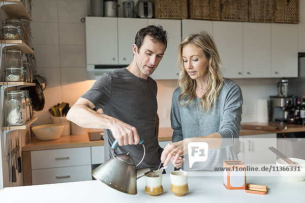 Mittleres erwachsenes Paar macht eine Tasse Tee in der Küche