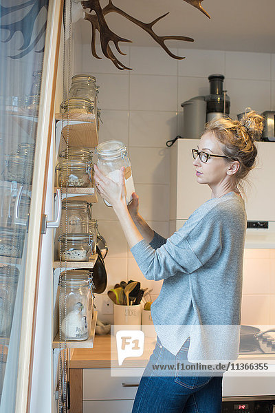 Frau liest Etikett auf Ofenglas in der Küche