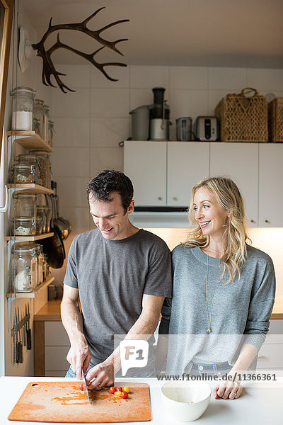 Mittleres erwachsenes Paar beim Schneiden von Kirschtomaten in der Küche