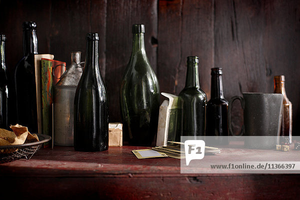 Leere alte Bierflaschen und Spielkarten im Kneipenregal