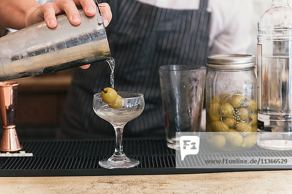 Nahaufnahme des Barkeepers beim Einschenken des Cocktails an der Cocktailbar
