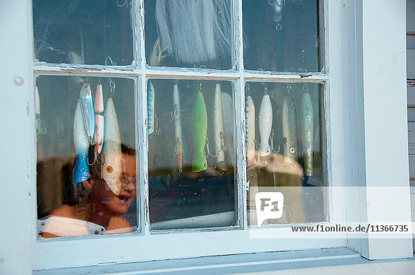 Spiegelung eines lächelnden Jungen im Fenster