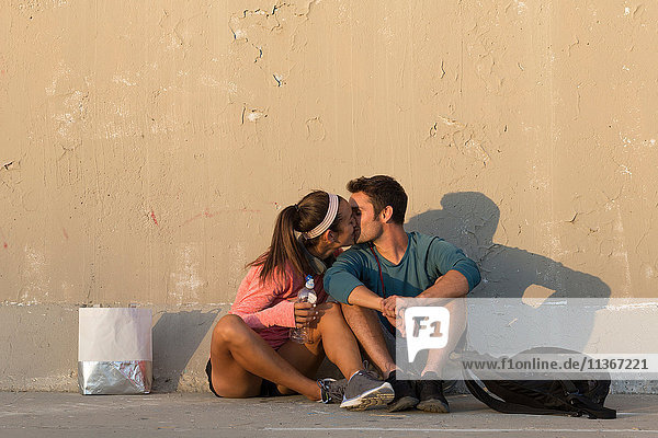 Pärchen küsst sich vor einer Betonwand