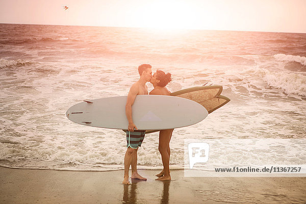 Romantisches junges Surferpaar küsst sich am Rockaway Beach  New York State  USA