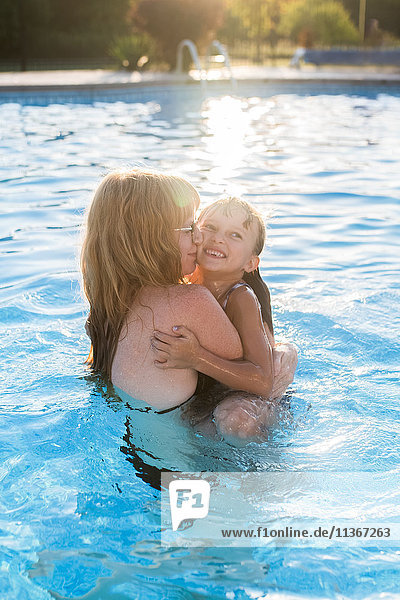 Mother and daughter in swimming pool  hugging