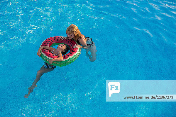 Mutter und Tochter halten sich im Schwimmbad an einem aufblasbaren Ring fest
