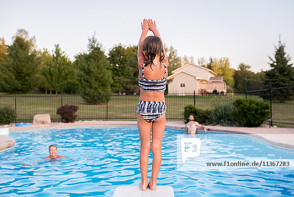 Junges Mädchen bereitet sich darauf vor  ins Schwimmbad zu springen  Vater und Großmutter schauen zu