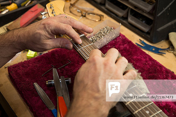 Beschnittene Ansicht der Hände des Gitarrenbauers bei der Herstellung der Gitarre