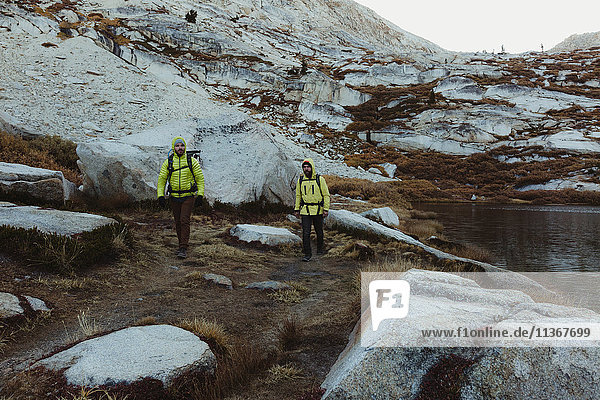 Two male hikers hiking by lake Mineral King Sequoia National Park California USA