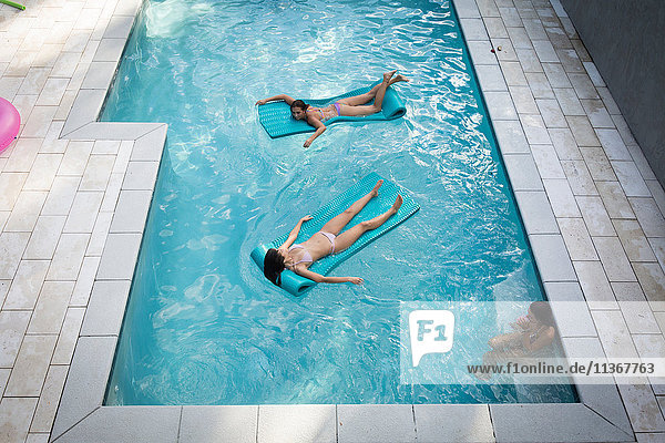 Hochwinkelaufnahme von zwei Frauen beim Sonnenbaden auf Hüpfburgen im Schwimmbad  Santa Rosa Beach  Florida  USA