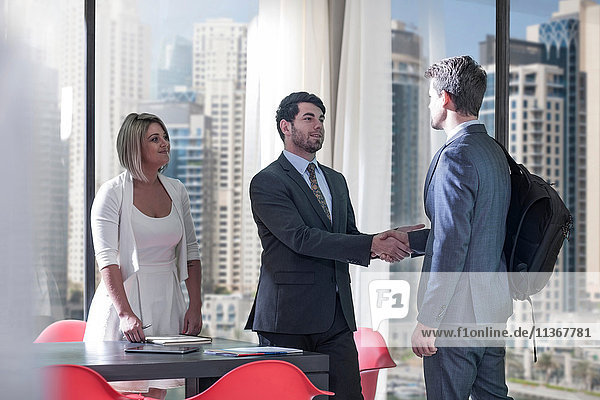 Businessmen and woman shaking hands in conference room