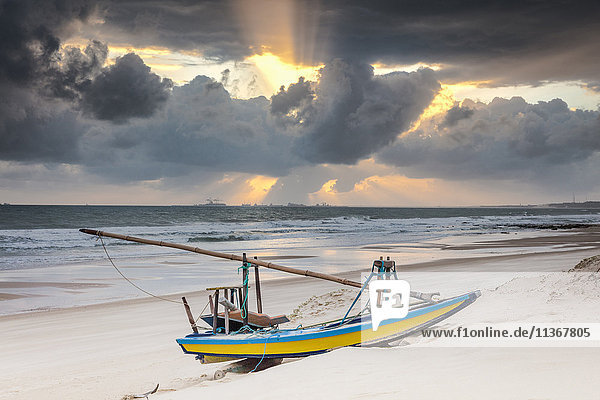 Fischerboot am Strand und dramatischer Himmel bei Sonnenuntergang  Taiba  Ceara  Brasilien