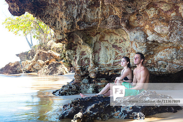 Junges Paar schaut aus einer Strandhöhle heraus  Taiba  Ceara  Brasilien