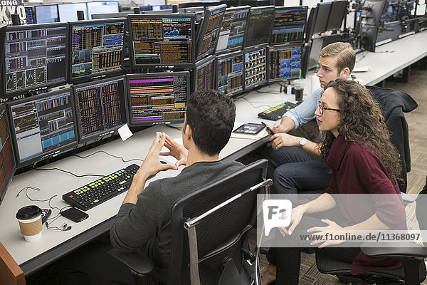 Group of young people analyzing stock market data at trading desk