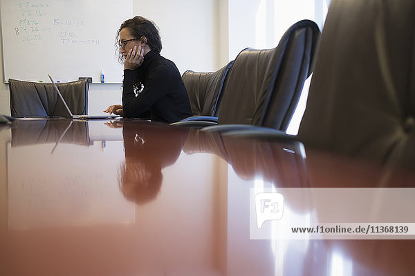 Junge Geschäftsfrau sitzt im Konferenzraum mit Laptop