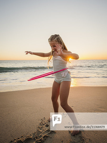 Mädchen (8-9) beim Drehen eines Plastikreifens am Strand