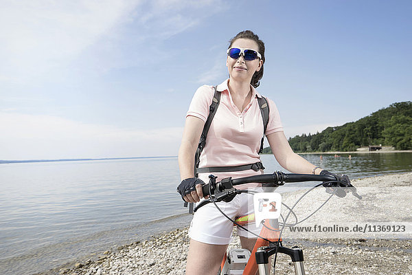 Mature woman with bicycle at lakeshore