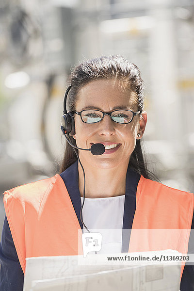 Porträt einer Ingenieurin mit Headset und Bauplan in einem geothermischen Kraftwerk