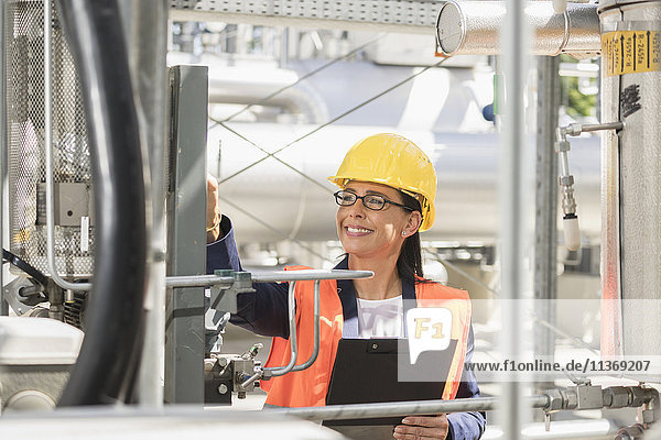 Female engineer smiling with document at geothermal power station