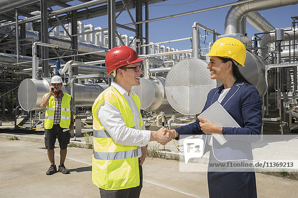 Businessman and engineer shaking hands at geothermal power station
