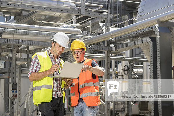 Engineer with his colleague in meeting with laptop at geothermal power station