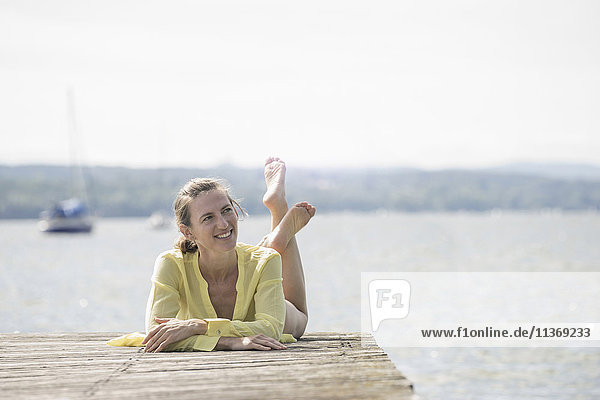 Thoughtful woman resting on boardwalk at the lake  Ammersee  Upper Bavaria  Germany