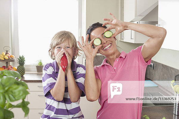 Woman with her son playing with vegetables in kitchen