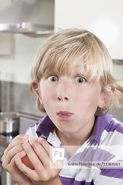 Boy eating an apple in kitchen