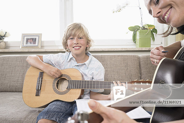 Woman with her son playing guitar in living room
