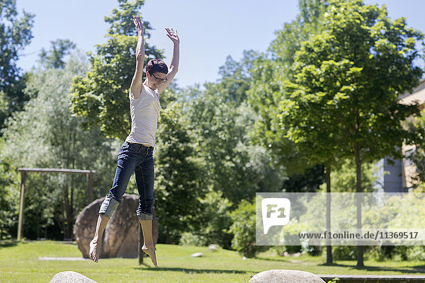 Mature woman jumping on rock in the park