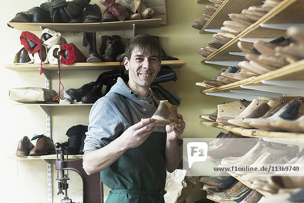 Portrait of a shoe maker holding a shoe stretcher in workshop